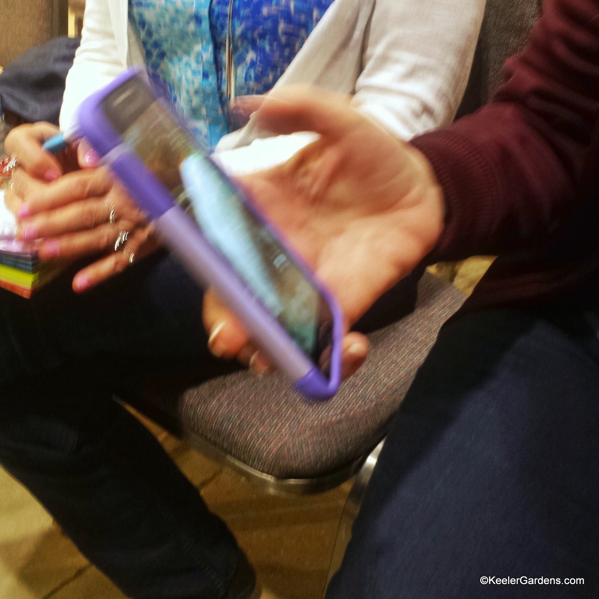 A student reviews the apps on her smart phone during a session on mobile photography. She appears to be eager to learn as her friend clasps her phone with some apprehension.